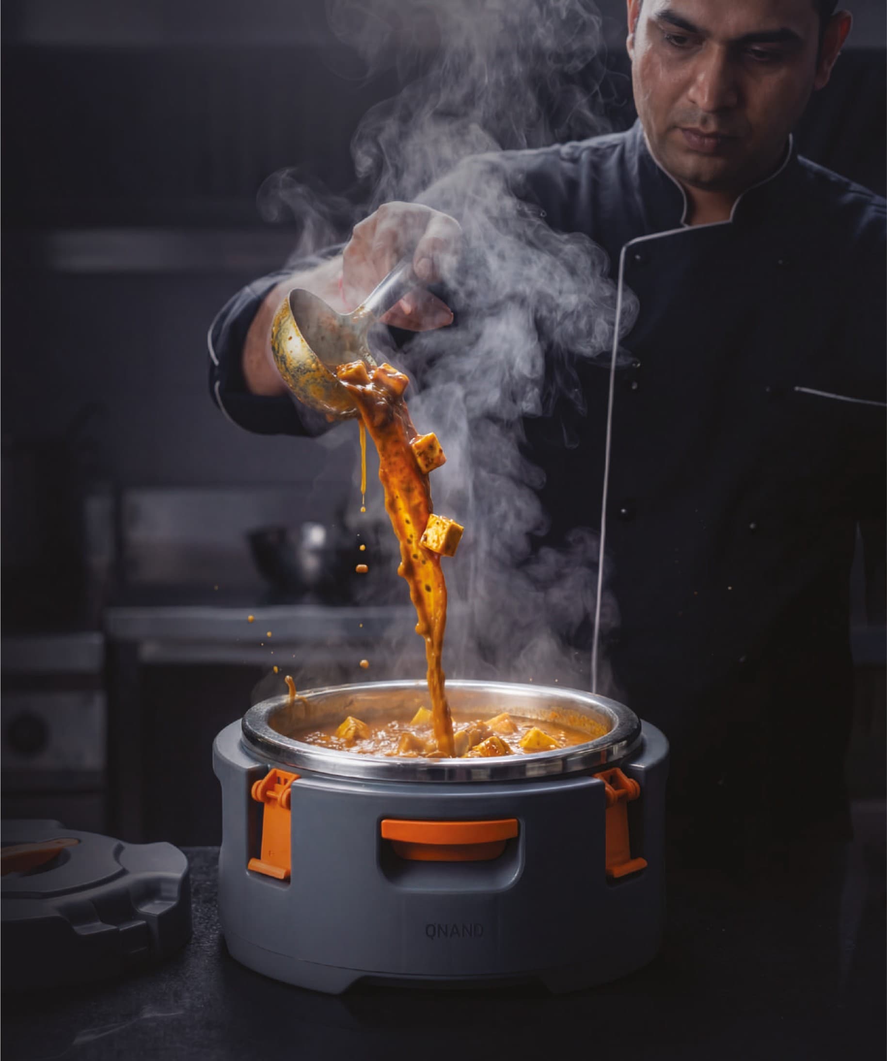 Chef serving hot curry into insulated food container